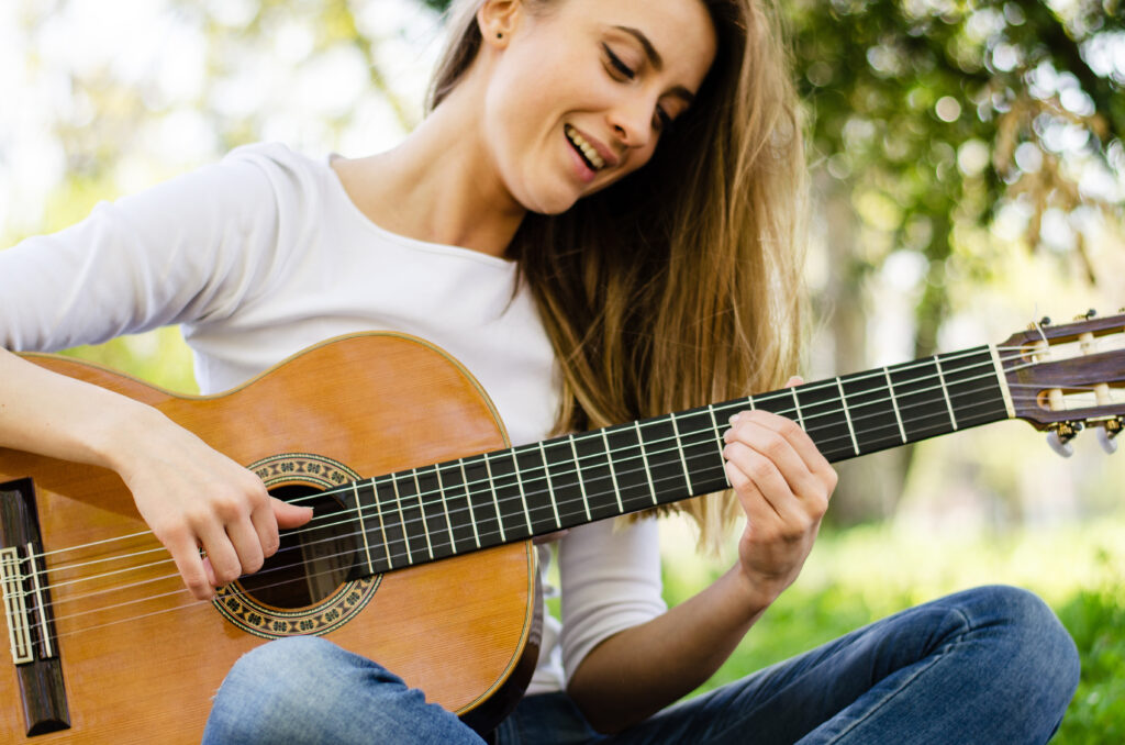 girl playing guitar outside